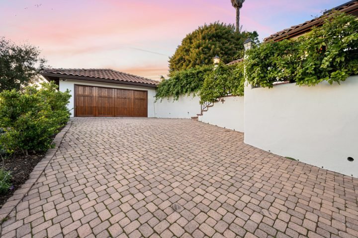 a driveway with brick pavers, and a garage in the background Brick paver driveway leading to a garage